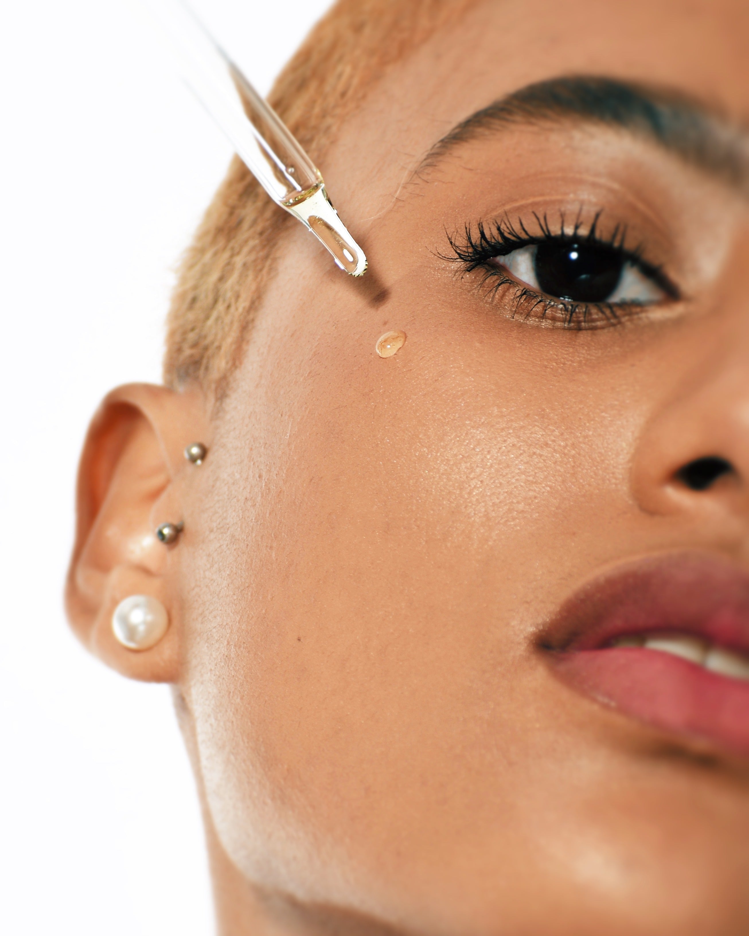 rose oil model with the dropper top on her cheek