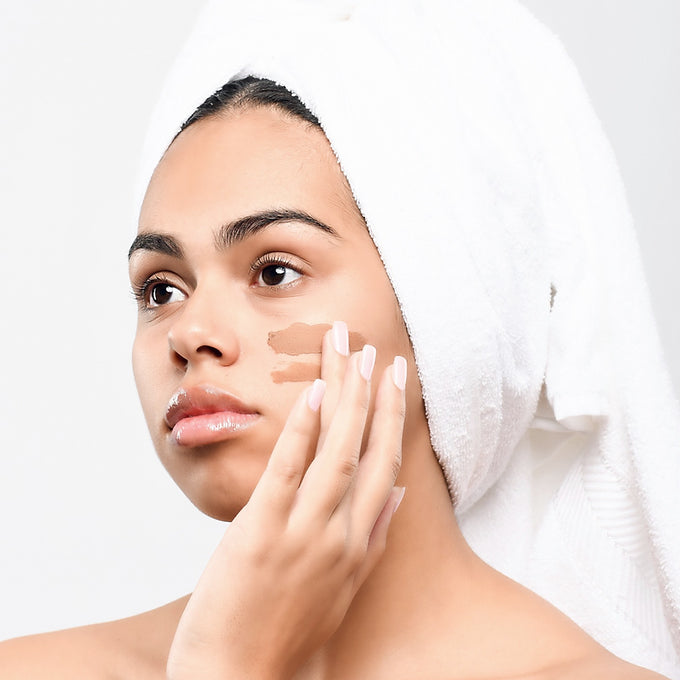 studio model with brown facial on her face with a towel on her head